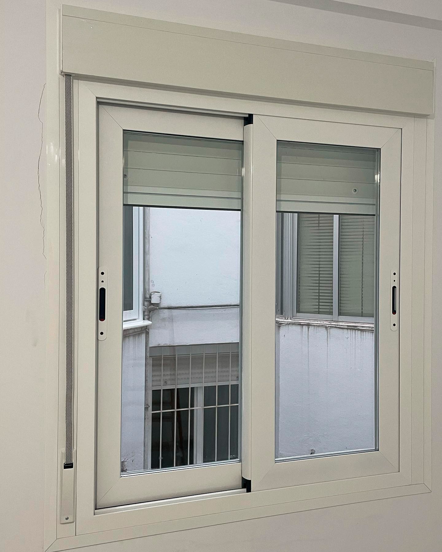 Ventana de aluminio blanco con persiana en dormitorio